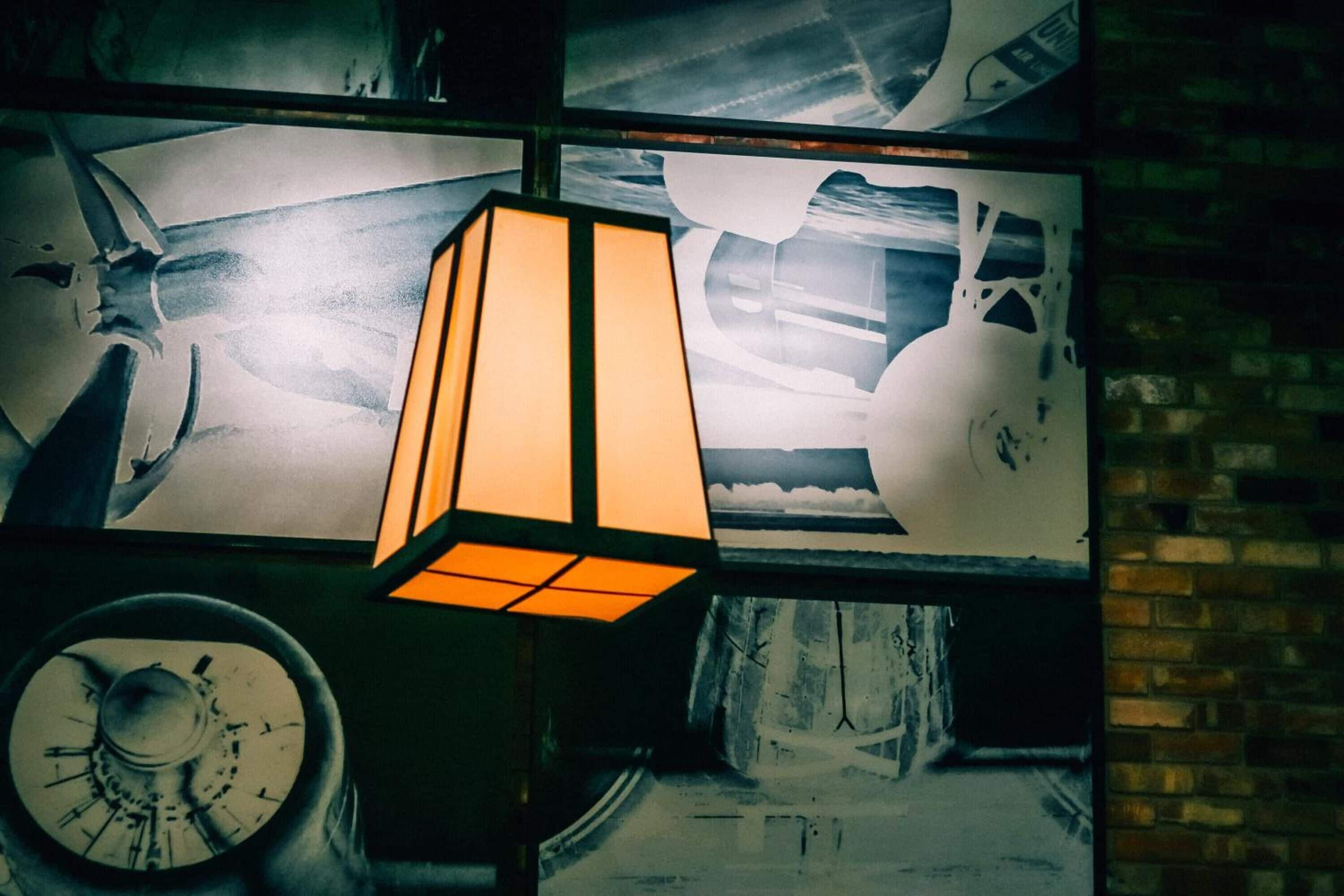 A wall with a large, rectangular, illuminated light fixture and a circular object below it.