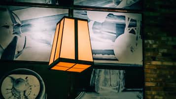 A wall with a large, rectangular, illuminated light fixture and a circular object below it.