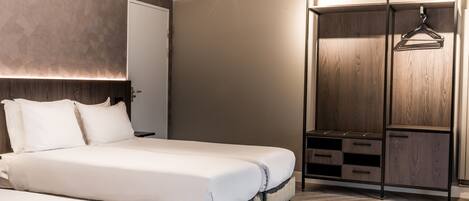 A modern bedroom with a large bed, bedside tables, a wardrobe, and a hanging rack.