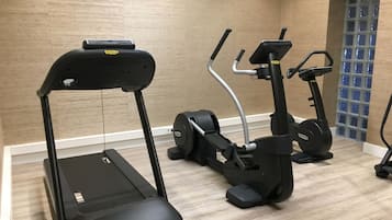 Un gimnasio con cinta de correr, elíptica y bicicleta estática.