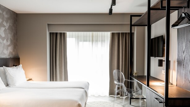 Ett hotellrum med en säng, ett skrivbord, en stol och en tv.