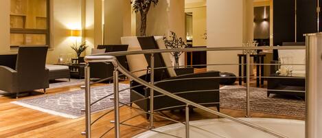 Una sala de estar moderna con una escalera, una planta grande y un comedor con una mesa y sillas.