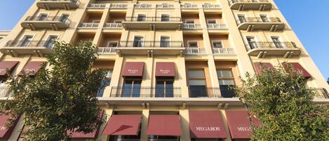 A multi-story hotel with balconies, large windows, and red awnings.