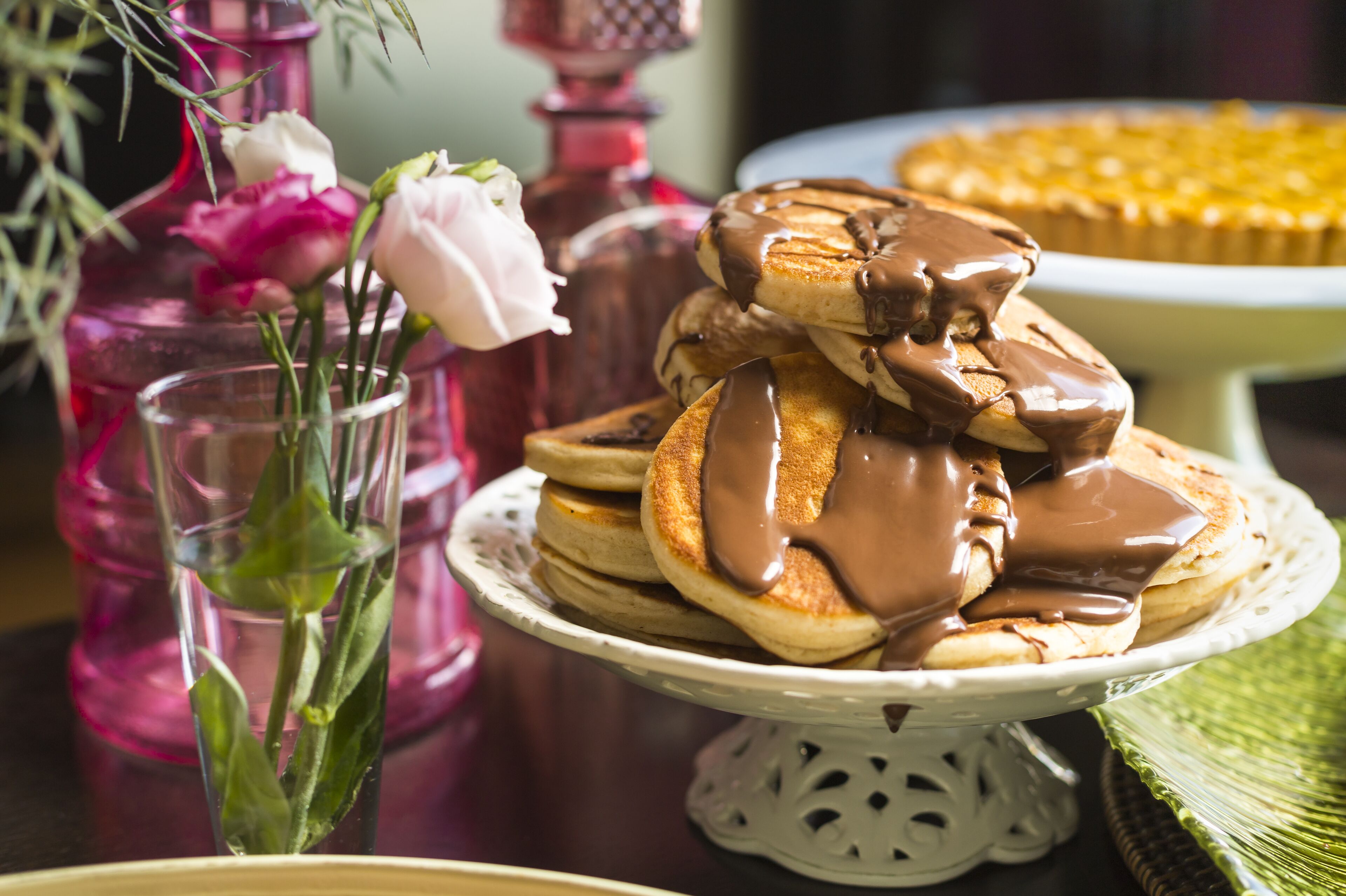 A stack of pancakes with chocolate sauce on a white plate.