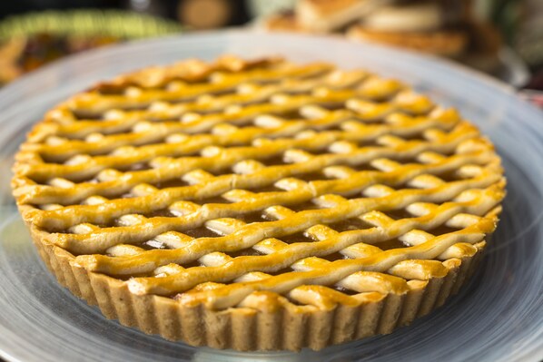 Tarta de frutas con corteza de rejilla sobre un plato de vidrio transparente.