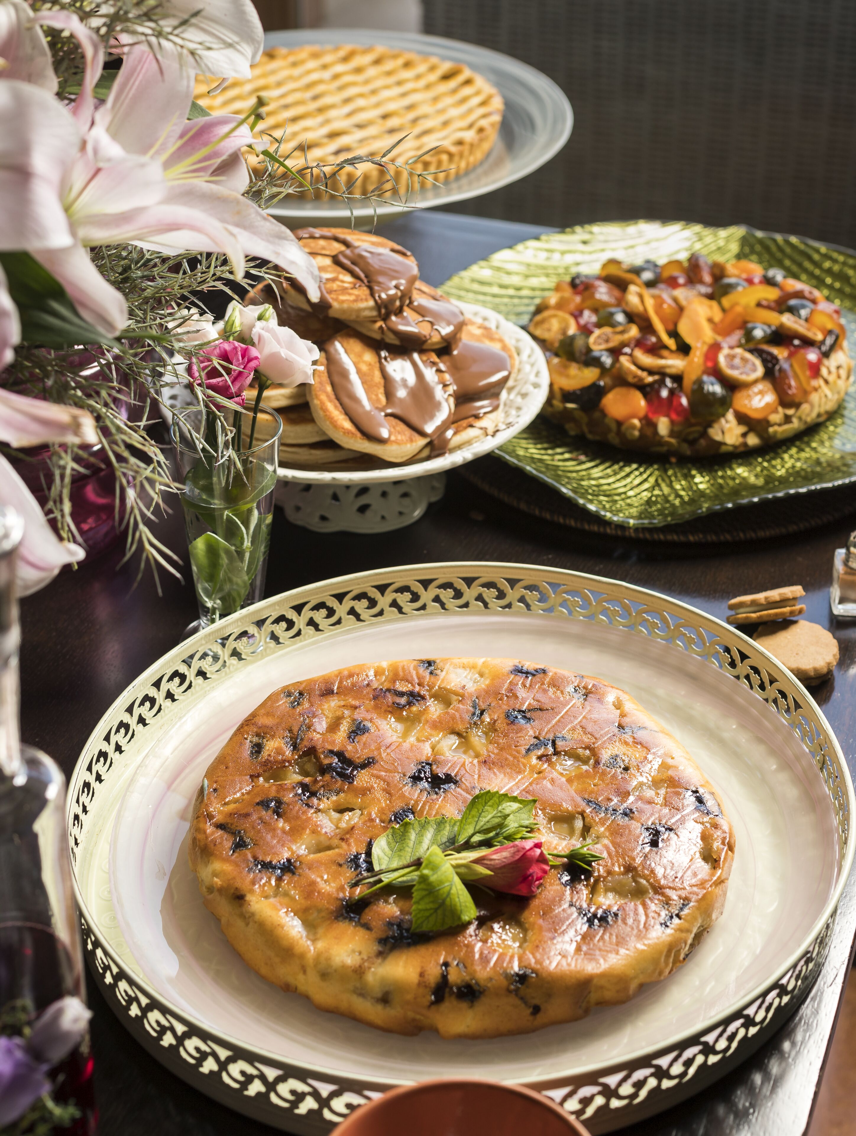 Una variedad de platos en una mesa, como una quiche, panqueques y una tarta.