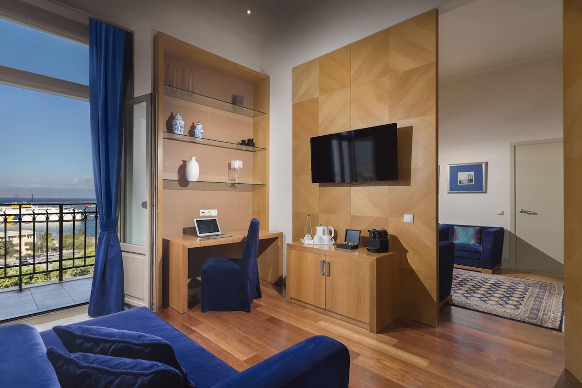 A modern living room with a wooden desk, a laptop, a television, and a sofa.