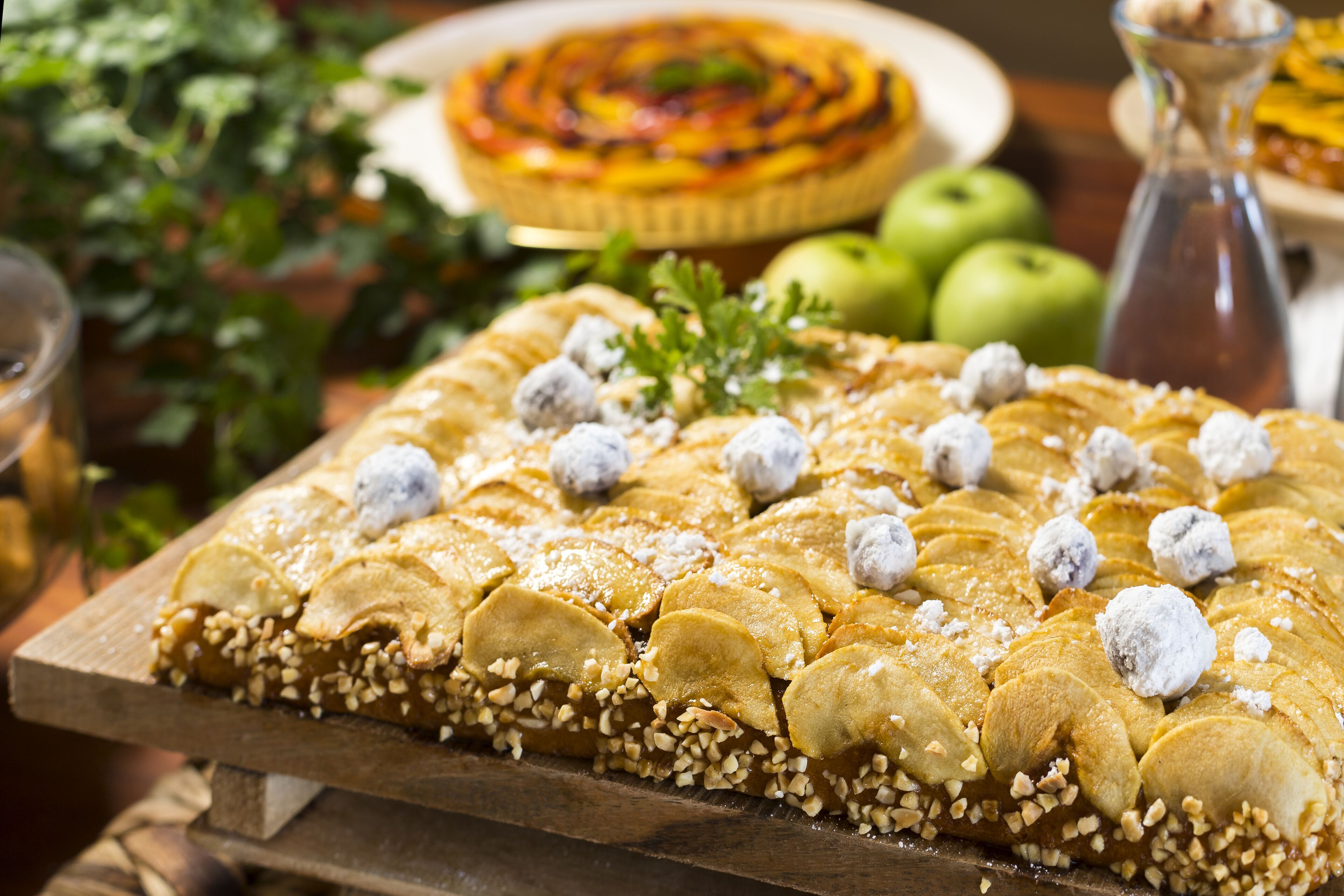 A dessert tray with a variety of pastries, including a tart and a pie, on a wooden board.