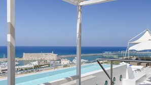 Un balcon doté d’un auvent blanc, d’où l’on a vue sur une piscine et la mer.