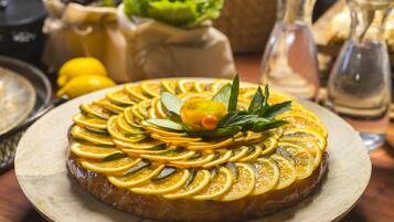 Una tarta redonda con rodajas de naranja y hojas de menta sobre una tabla de madera.