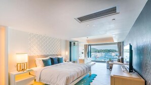 Habitación de hotel moderna con cama, mesita de noche, lámpara y vistas al mar.