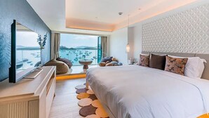 Una habitación de hotel moderna con una cama grande, televisión y vistas al mar, además de un diseño de pared geométrico único.