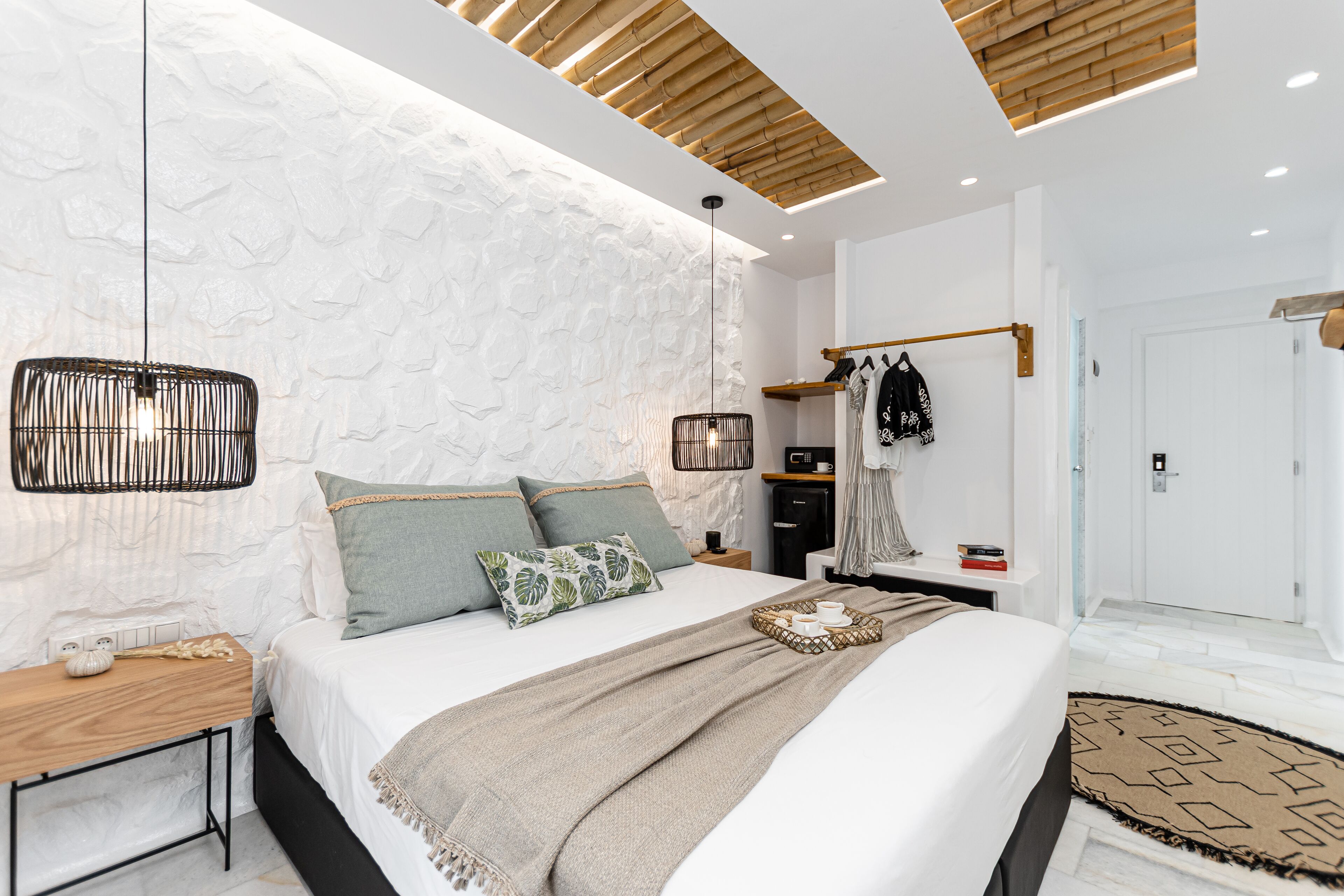A modern bedroom with a large bed, a bedside table, a hanging light fixture, and a wardrobe.