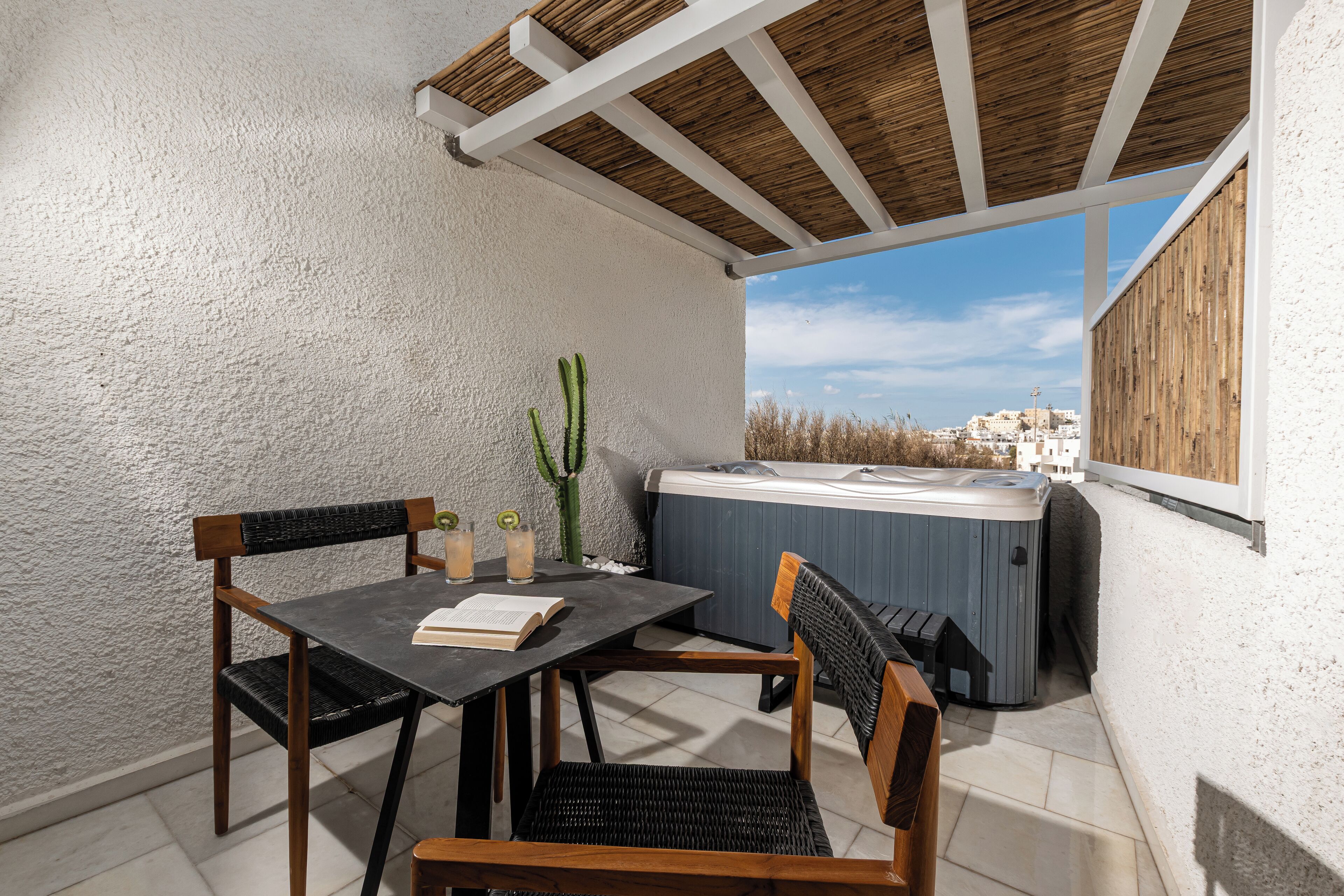 Een terras met een tafel, stoelen, een jacuzzi en een cactuspunt.