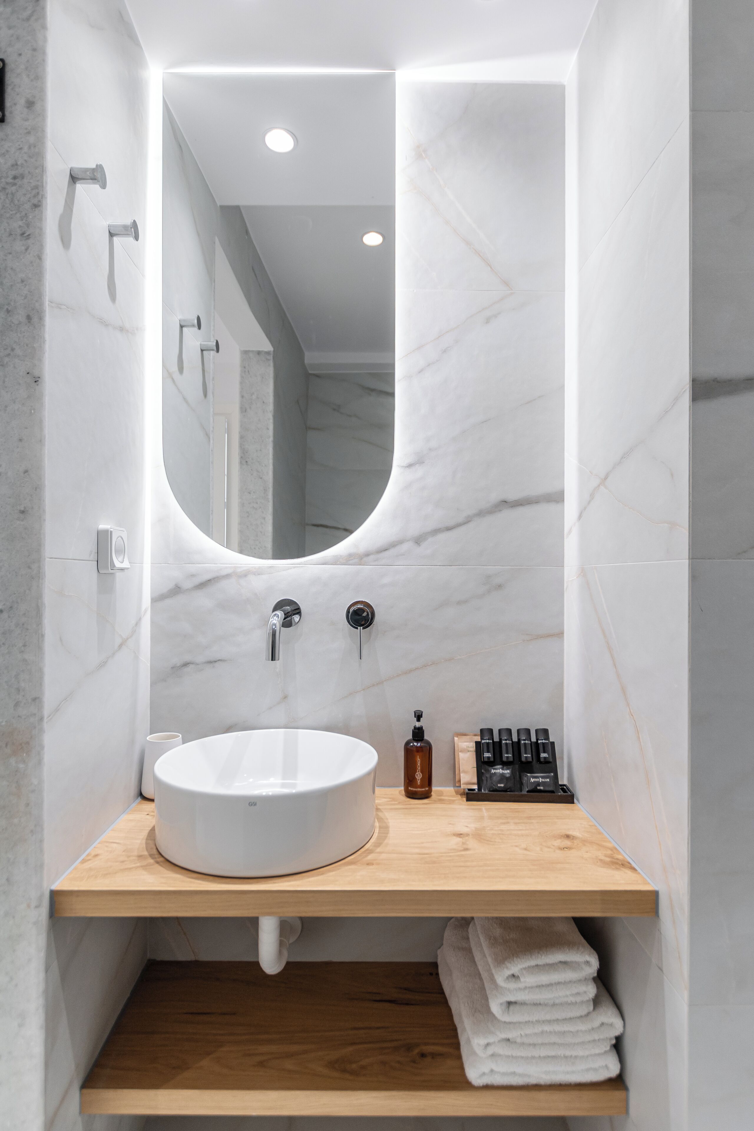 A modern bathroom with a white marble sink, wooden vanity, and a large mirror.
