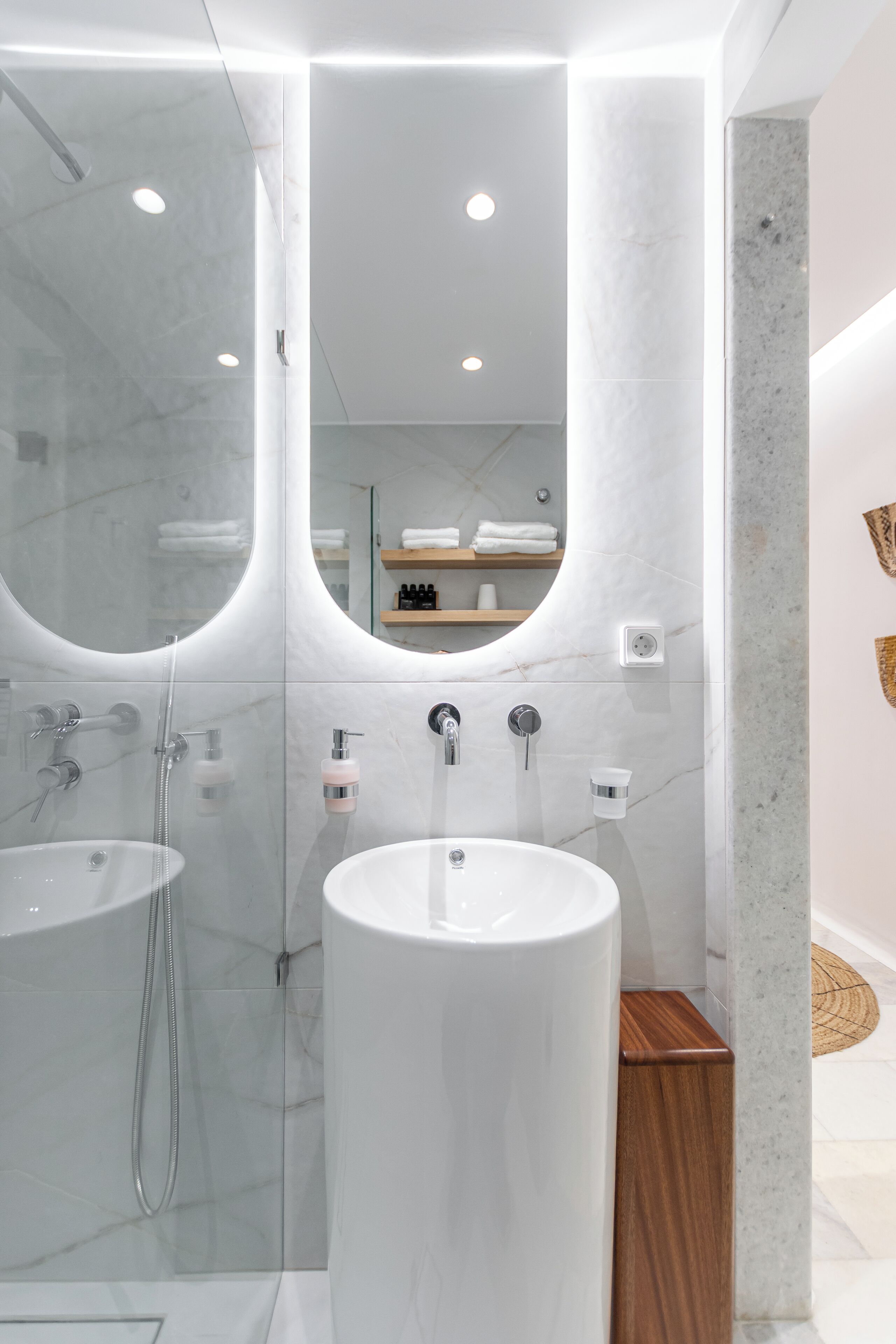 A modern bathroom with a glass-enclosed shower, a central sink, and a mirror.