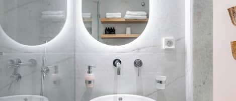 A modern bathroom with a glass-enclosed shower, a central sink, and a mirror.