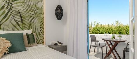 A bedroom with a bed, a nightstand, a hanging lamp, and a balcony with a table and chairs.