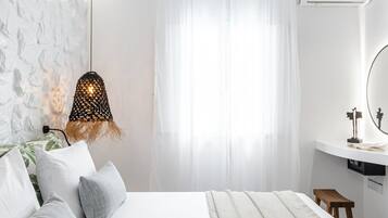 A modern bedroom with a large bed, a bedside table, a hanging lamp, and a window with sheer curtains.