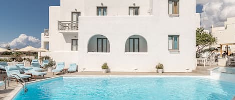 Una piscina al aire libre, sombrillas, sillones reclinables de piscina