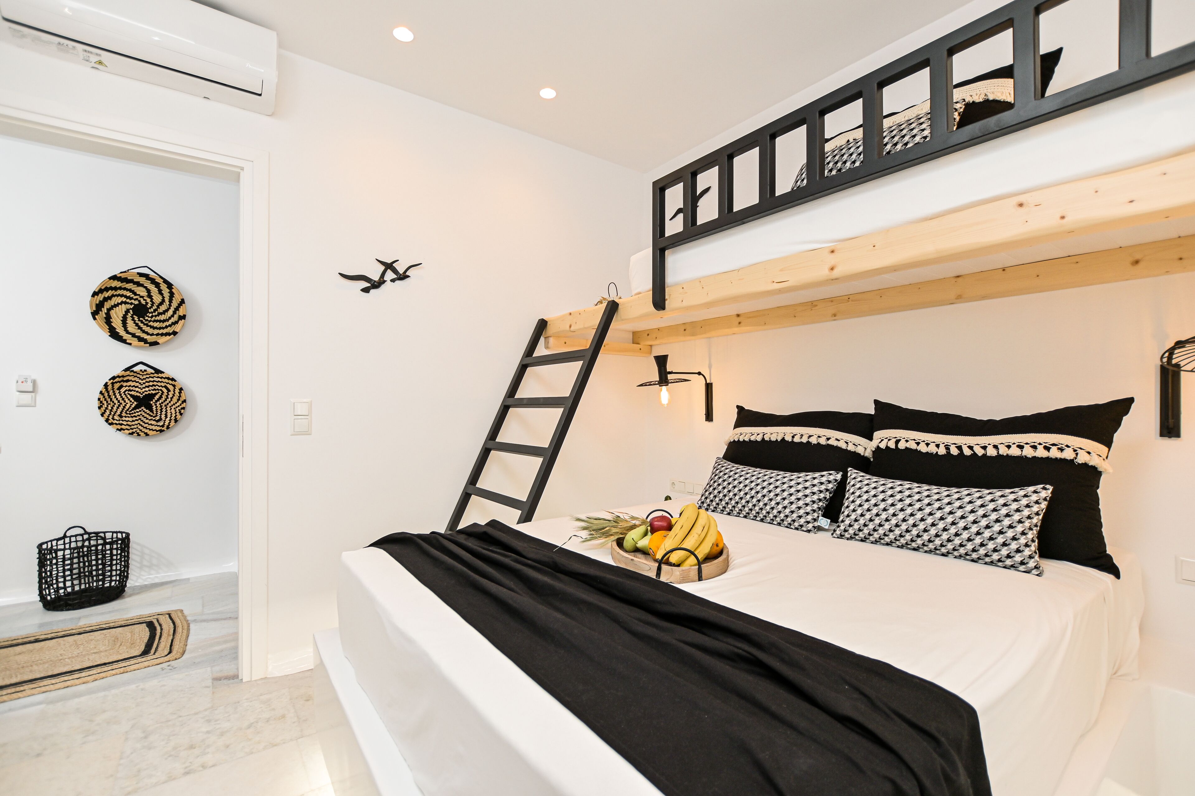 A modern bedroom with a bunk bed, a ladder, a fruit bowl, and decorative wall art.