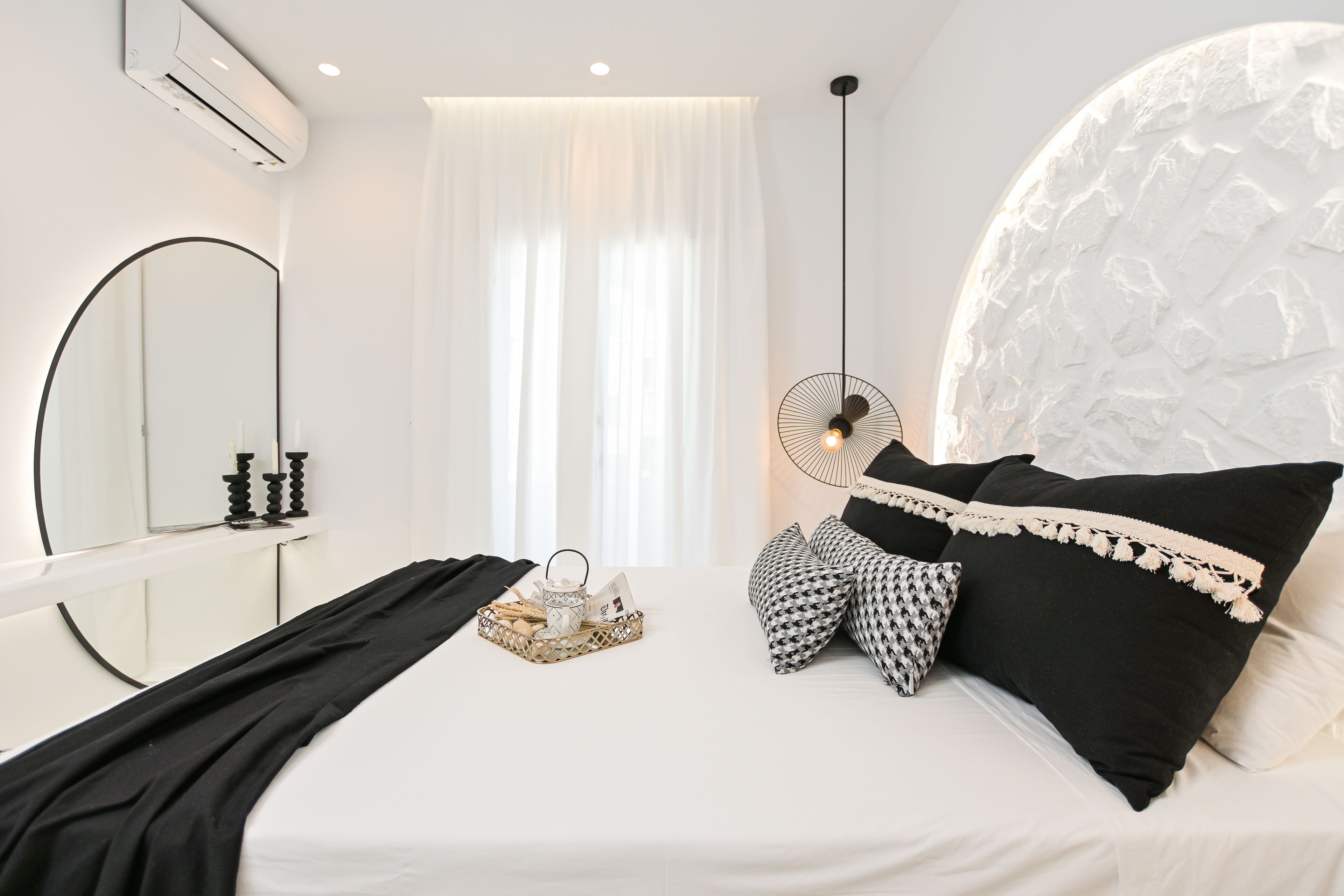 Una camera da letto con un letto, un comodino con un cesto, una ventola a soffitto e un grande specchio.