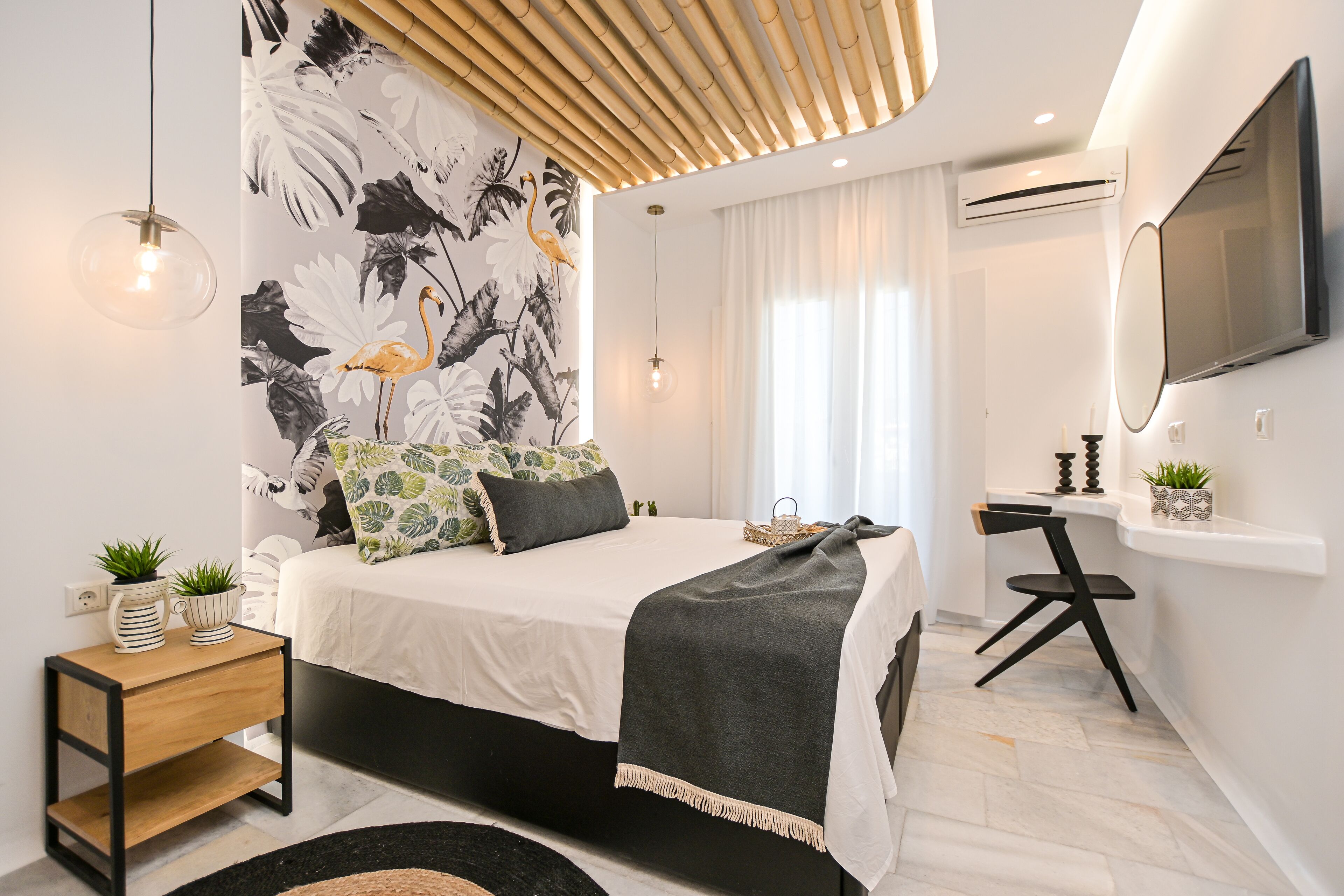 A modern bedroom with a bed, bedside tables, a desk, and a large mirror.