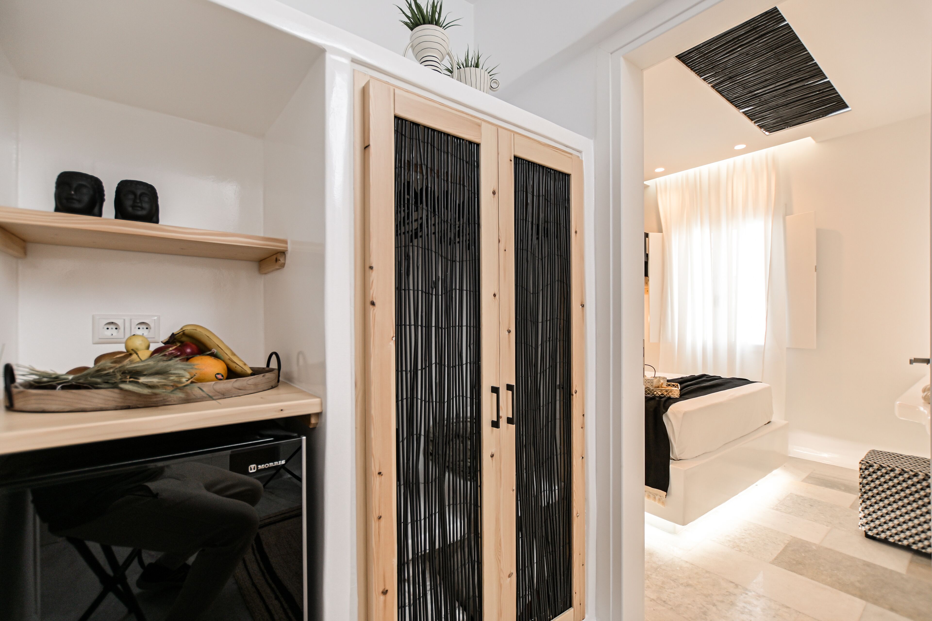 A modern kitchen with a wooden countertop, a black chair, and a fruit bowl.