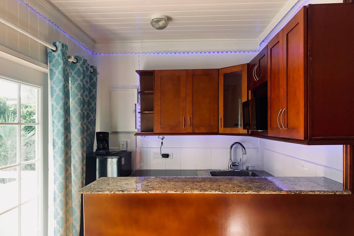Una cocina con armarios de madera, encimera de granito, un fregadero y una lámpara en el techo.