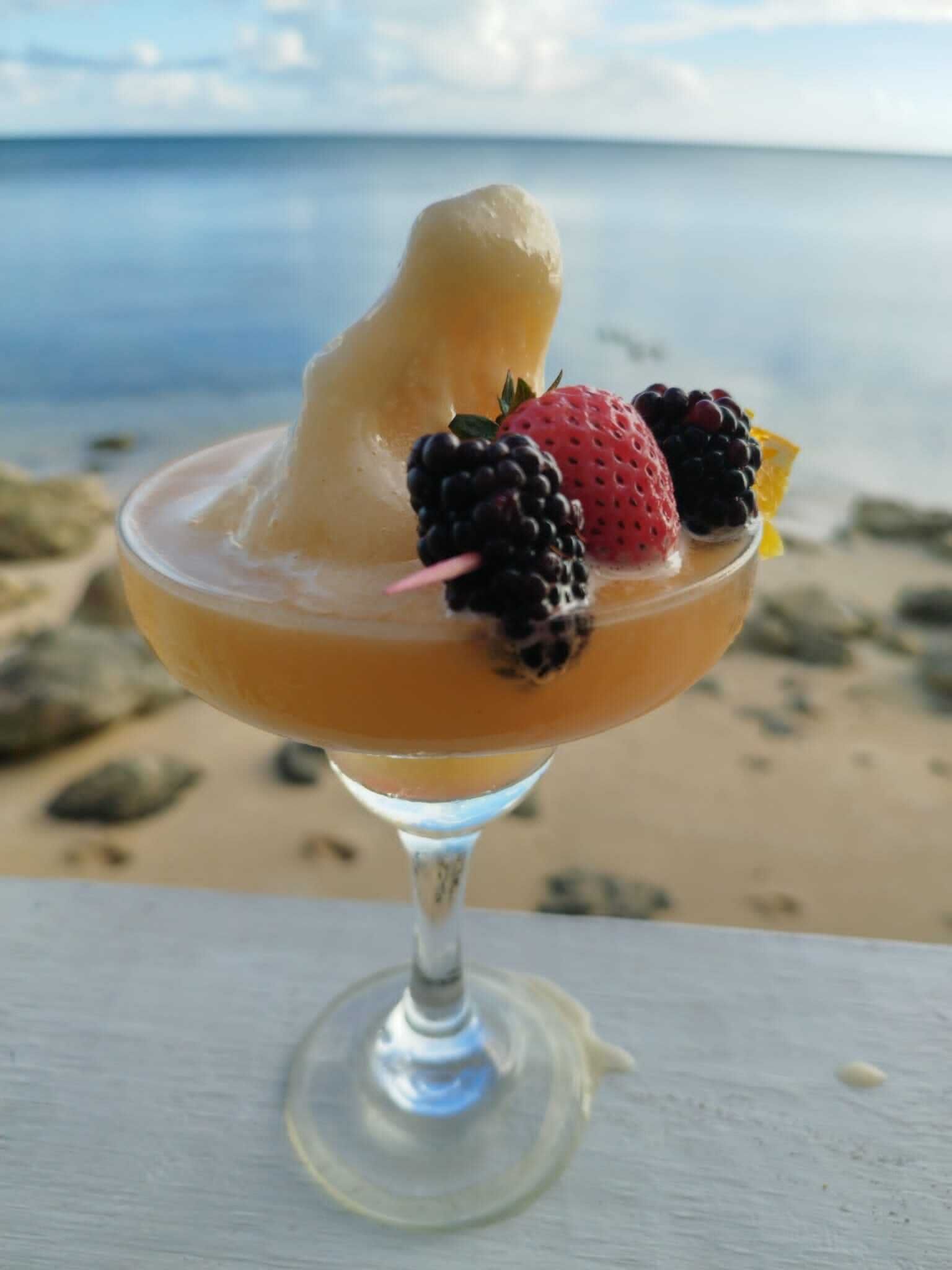 Cóctel con guarnición de frutas en una playa.