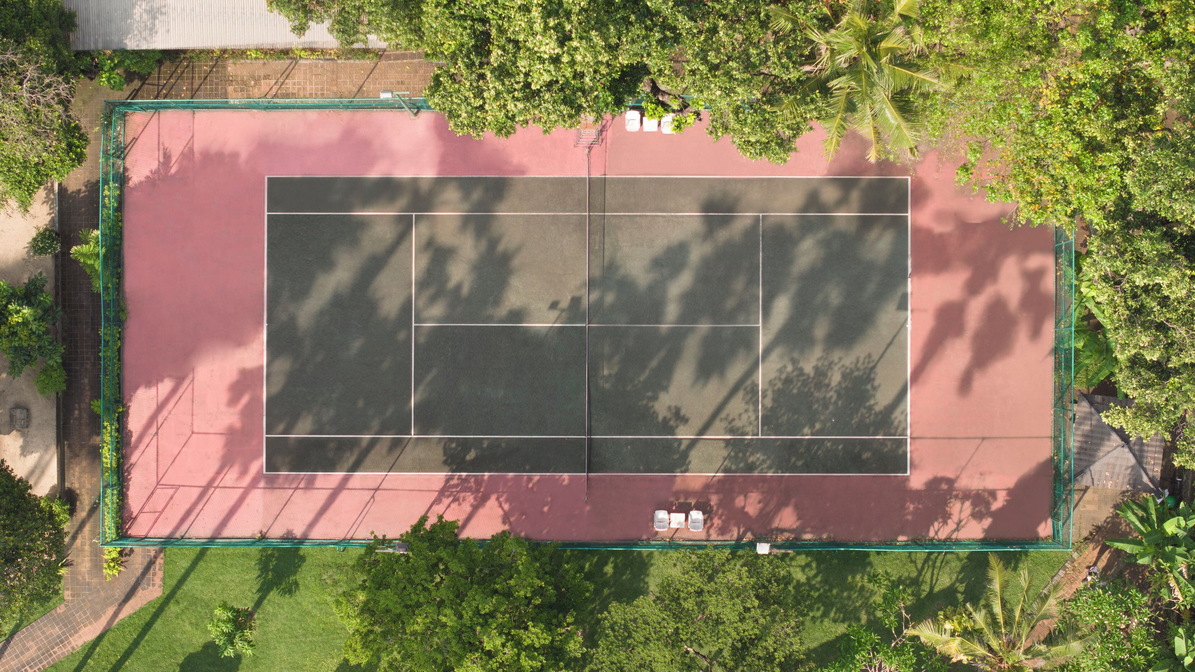 Vista aérea de una cancha de tenis rodeada de árboles y follaje.