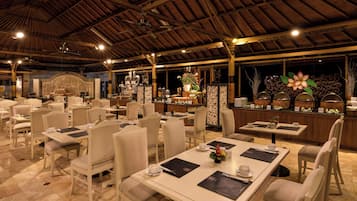 A spacious dining area with multiple tables and chairs, a central bar area, and decorative elements.