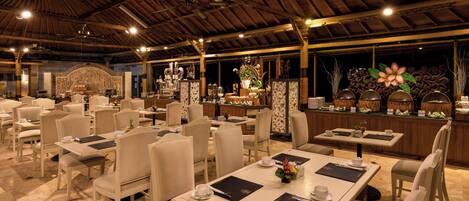 A spacious dining area with multiple tables and chairs, a central bar area, and decorative elements.