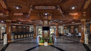 A spacious lobby with wooden columns, a central decorative fountain, and a reception desk. - The Jayakarta Bali (Legian)