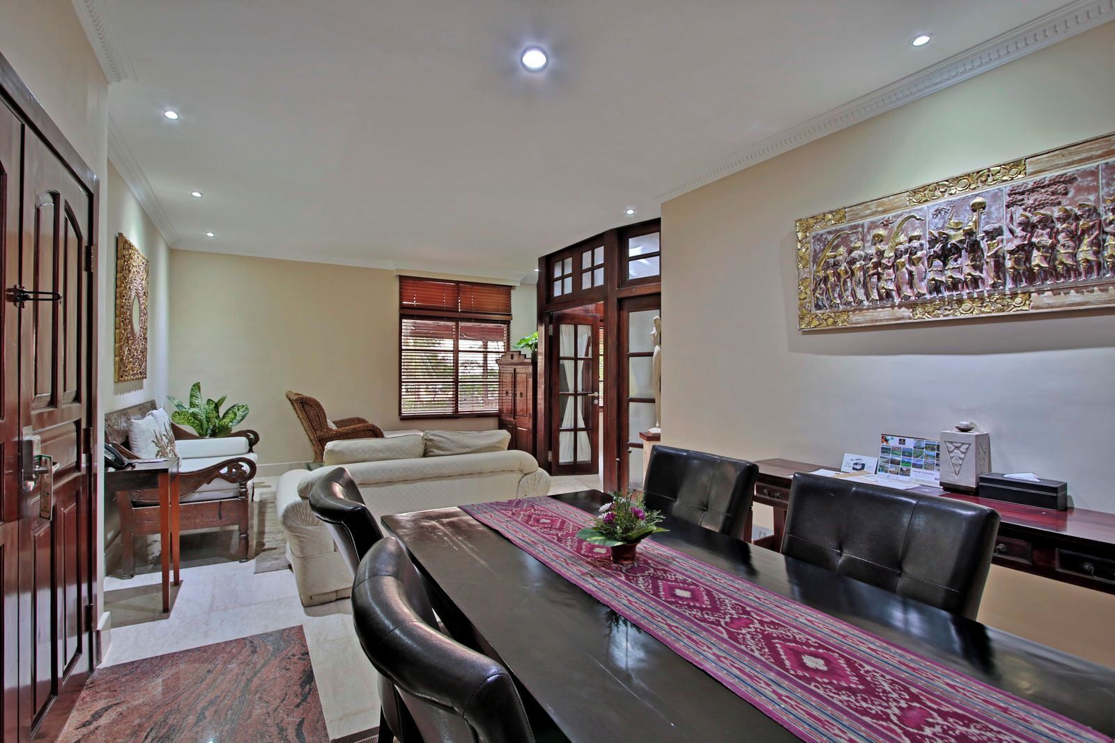 A conference room with a long table, leather chairs, a sofa, and a decorative wall piece.