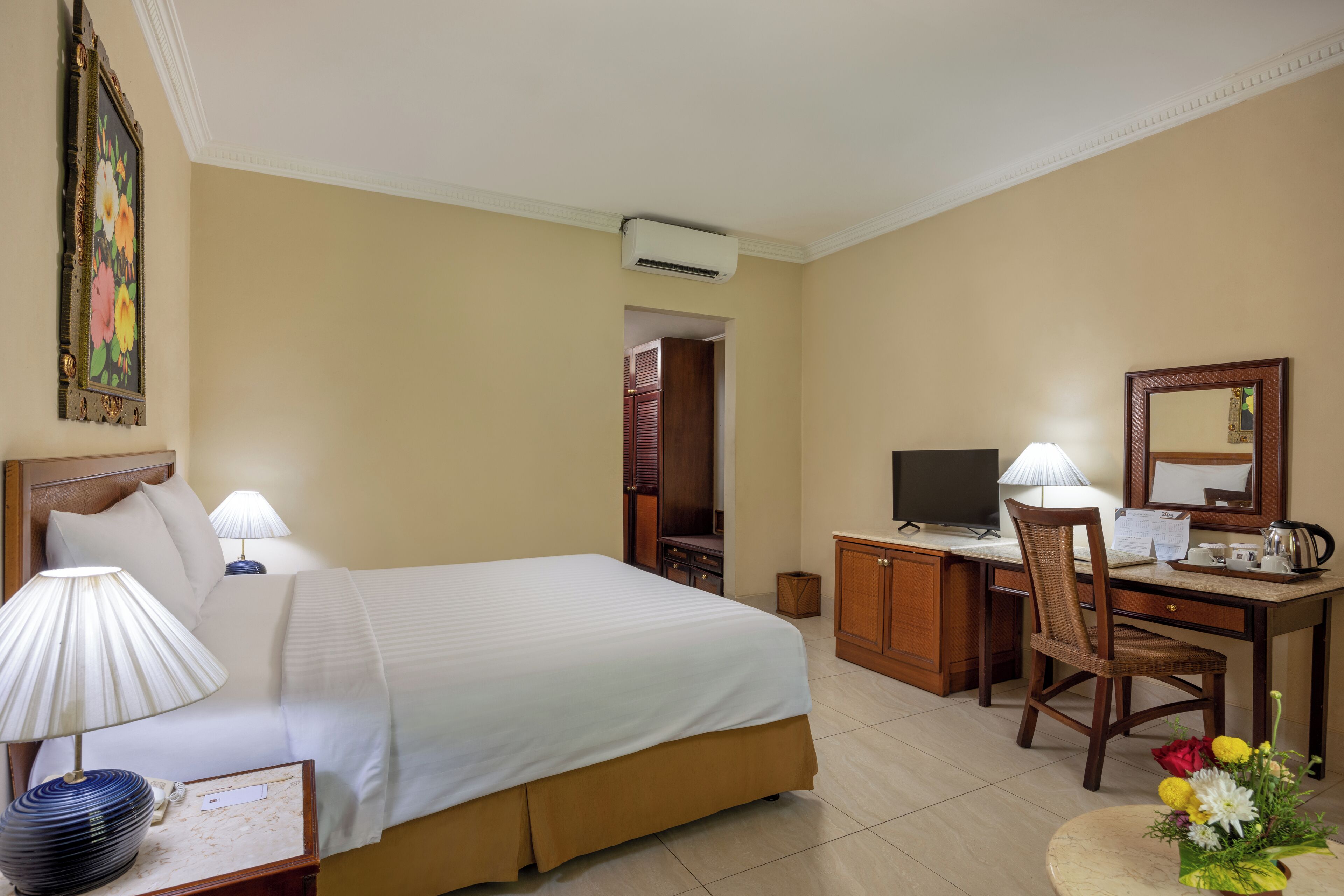 Une chambre d’hôtel comprenant un lit, des lampes de chevet, un bureau avec une chaise, une télévision et un miroir.