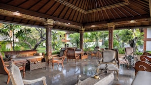 A spacious, elegantly furnished lounge with a polished floor, comfortable seating, and a view of lush greenery outside. - The Jayakarta Bali (Legian)