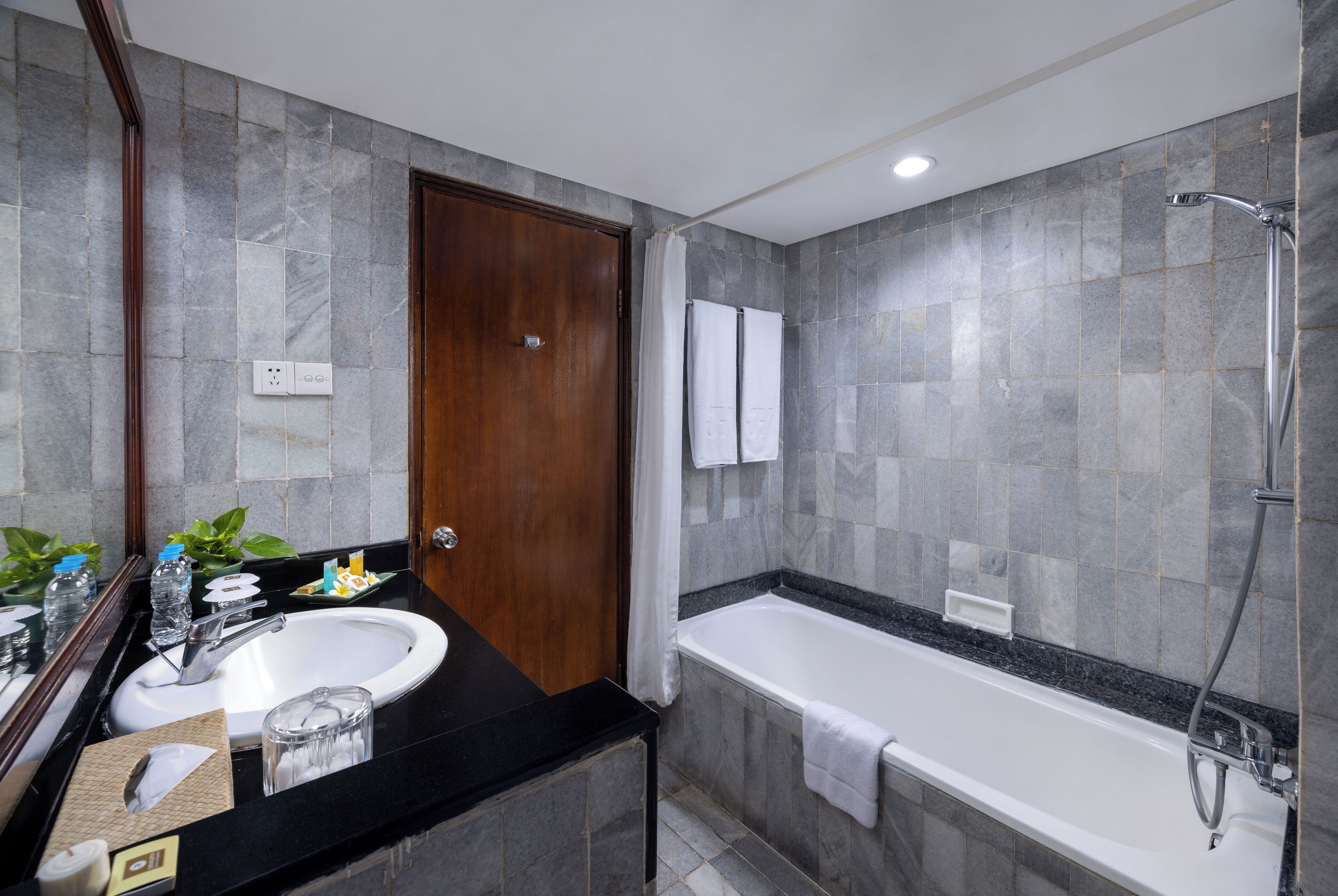 A modern bathroom with a black countertop, white sink, and a separate shower area.