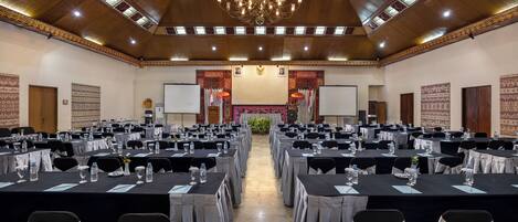 A conference room with rows of tables, chairs, and a chandelier.