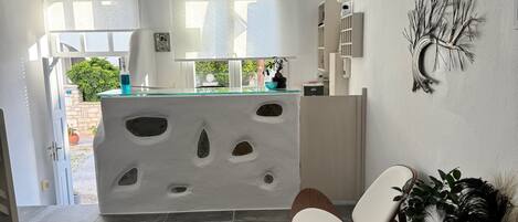 Una cocina moderna con una isla central, un comedor con una silla y vistas al exterior.