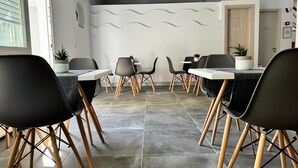 A modern dining area with black chairs and wooden legs, a tiled floor, and a wall with a wavy pattern.