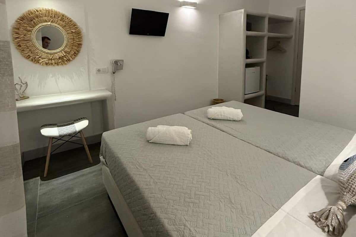 A modern hotel room with a bed, a desk, a chair, a TV, and a wardrobe.