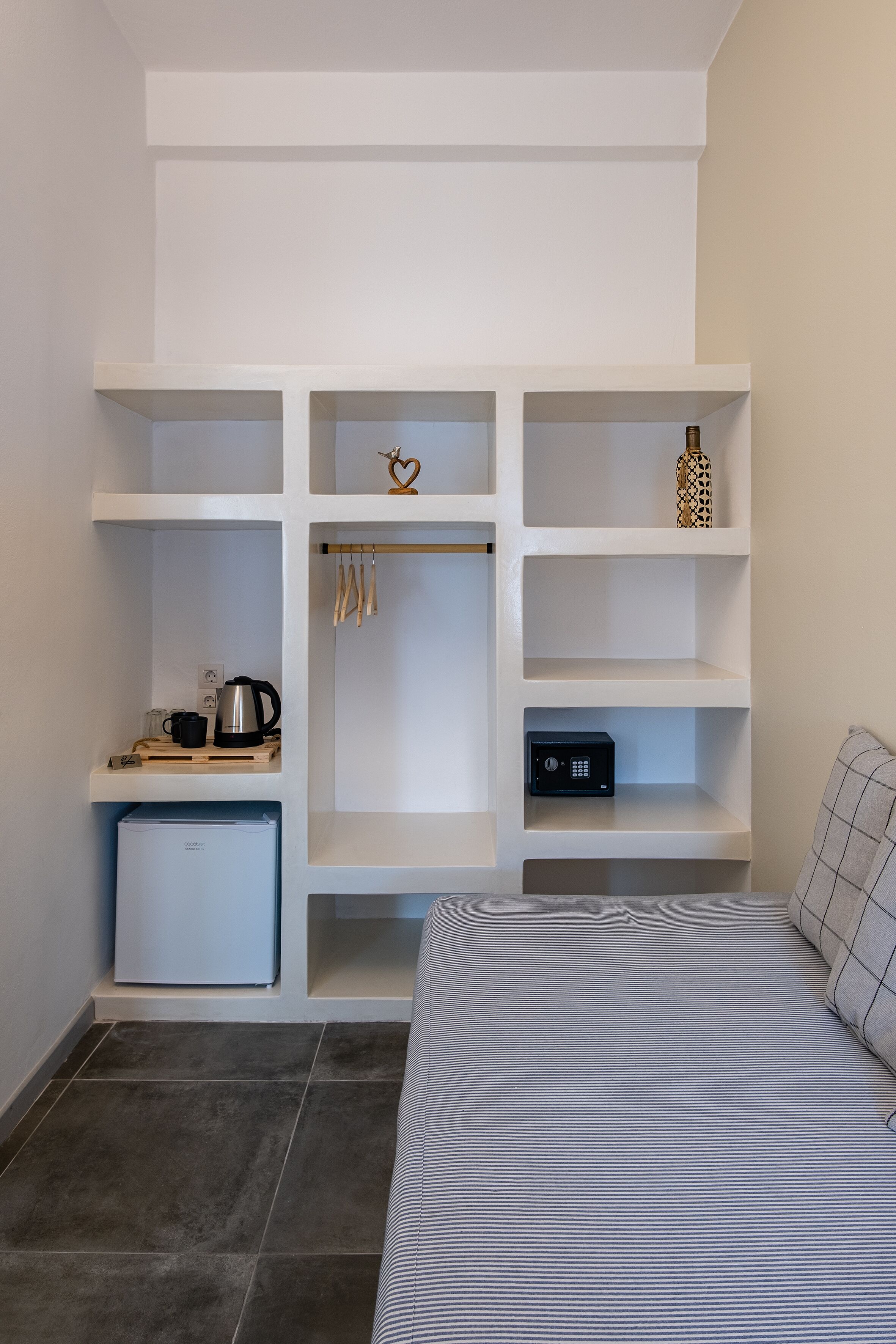 Une chambre compacte comprenant un lit, une petite kitchenette, une armoire intégrée et un coffre-fort.