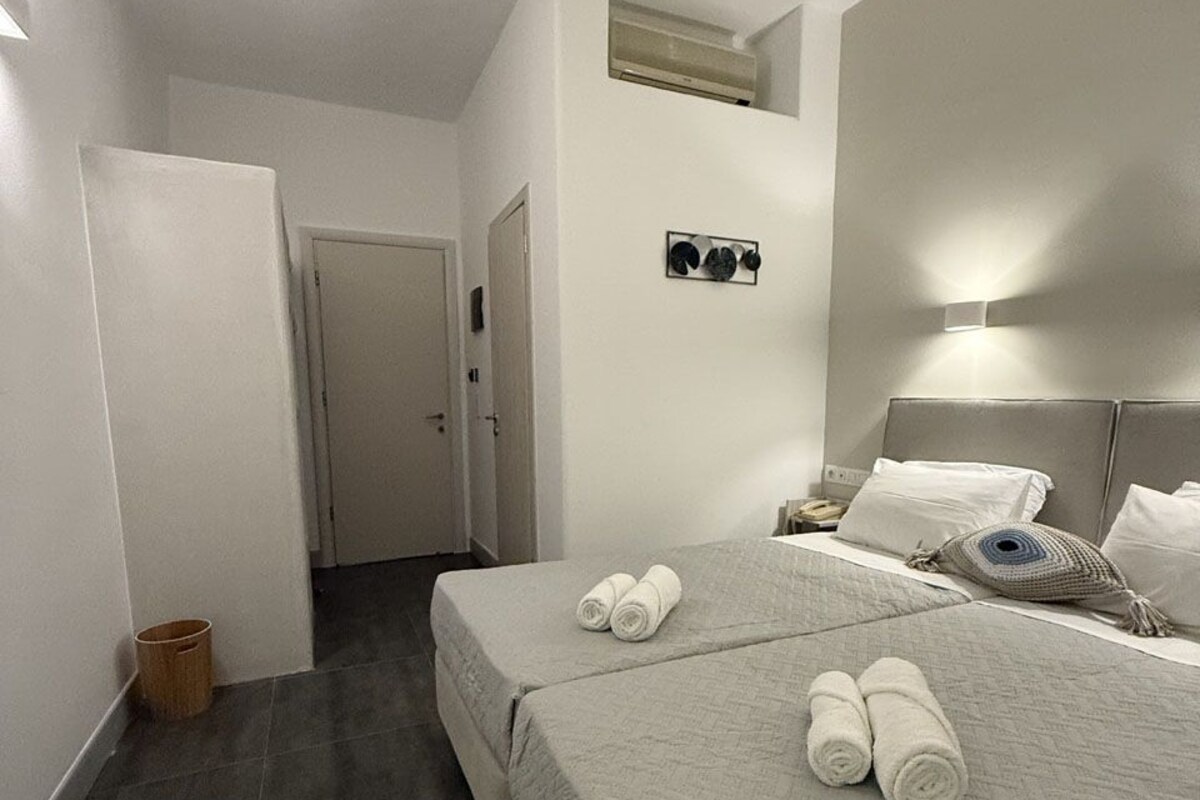 Hotellihuone, jossa on kaksi sänkyä, pieni kylpyhuone ja käytävä.