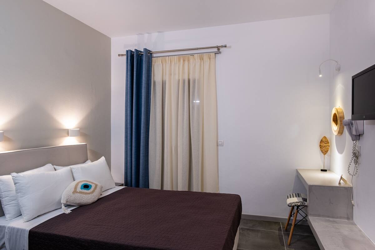A modern hotel room with a bed, bedside lamps, a desk, and a TV.