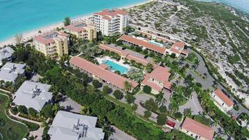 An aerial view of a resort with multiple buildings, a swimming pool, and a beach.