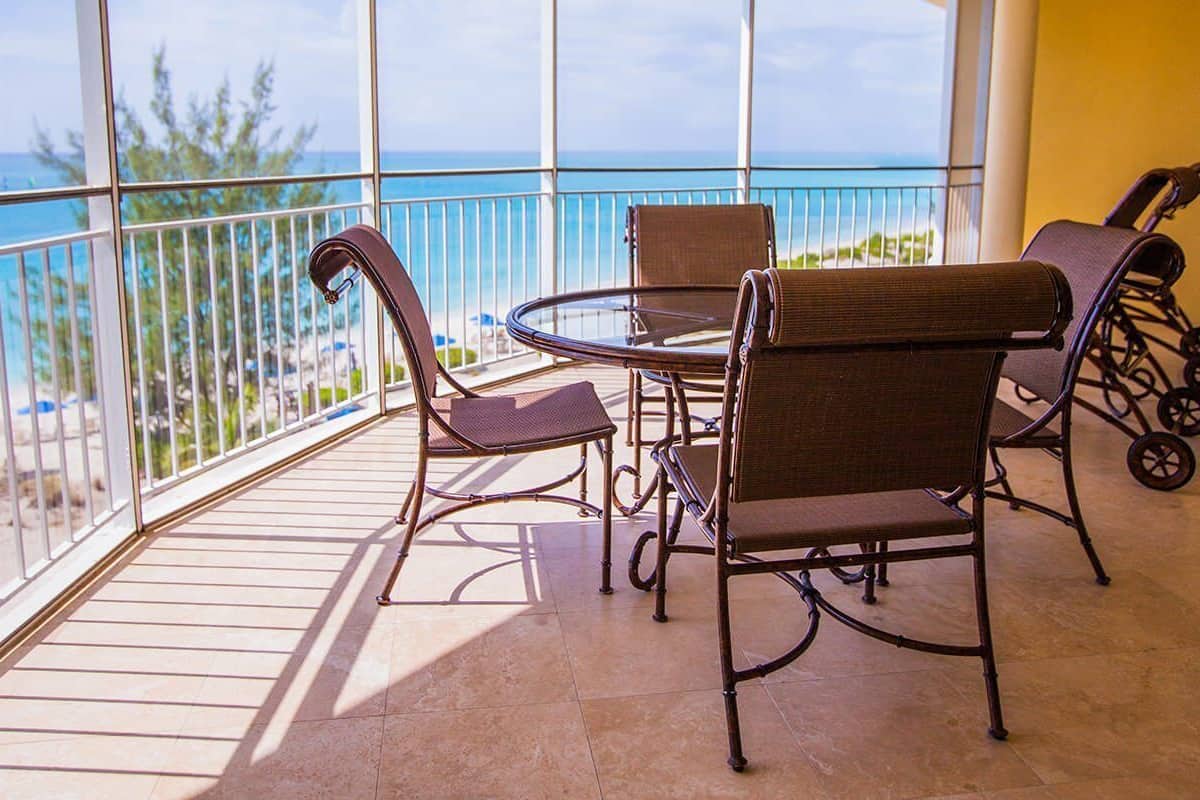 Un balcon avec vue sur l’océan, une table ronde et deux chaises en osier.