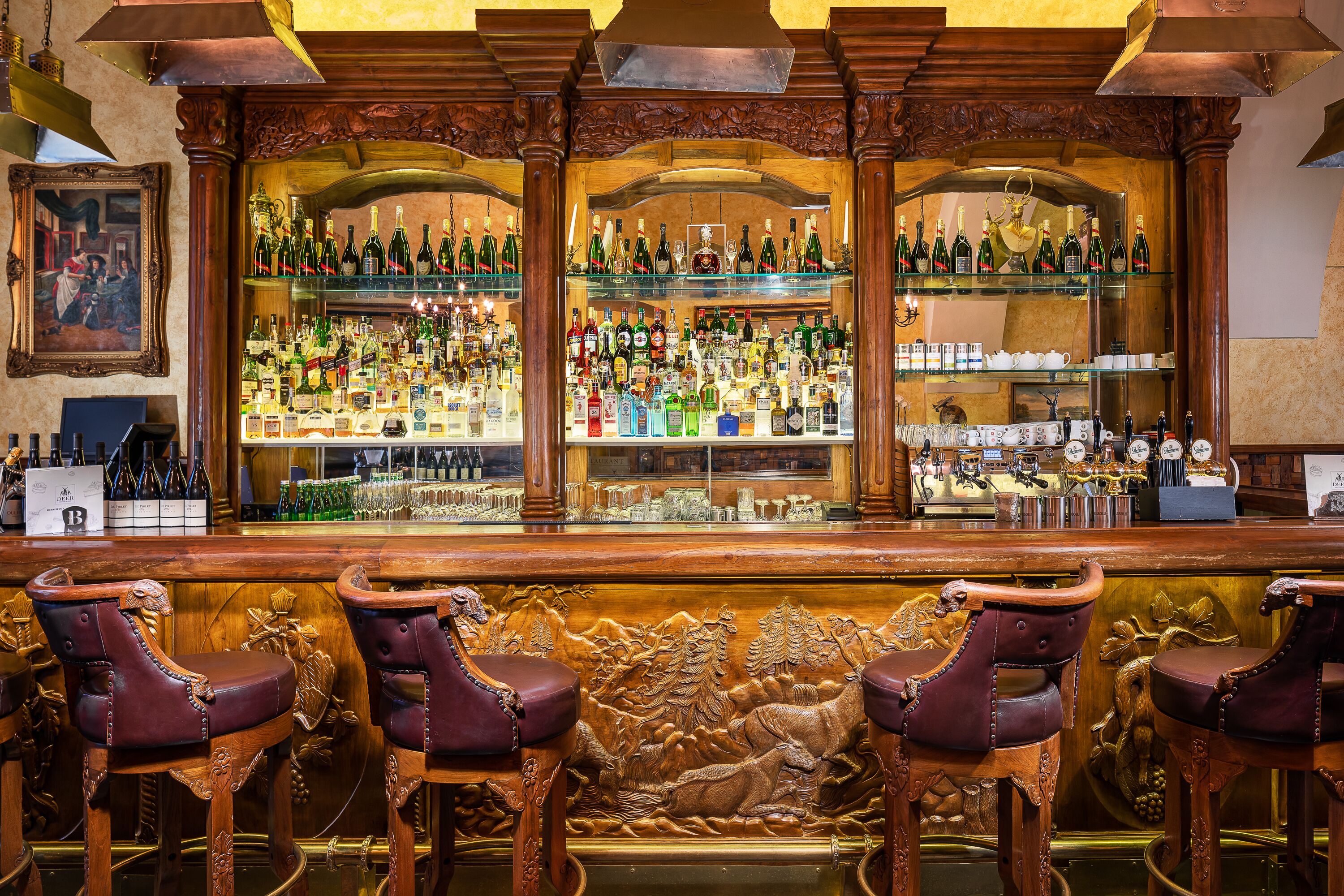 A bar with wooden bar stools and shelves of various liquor bottles.