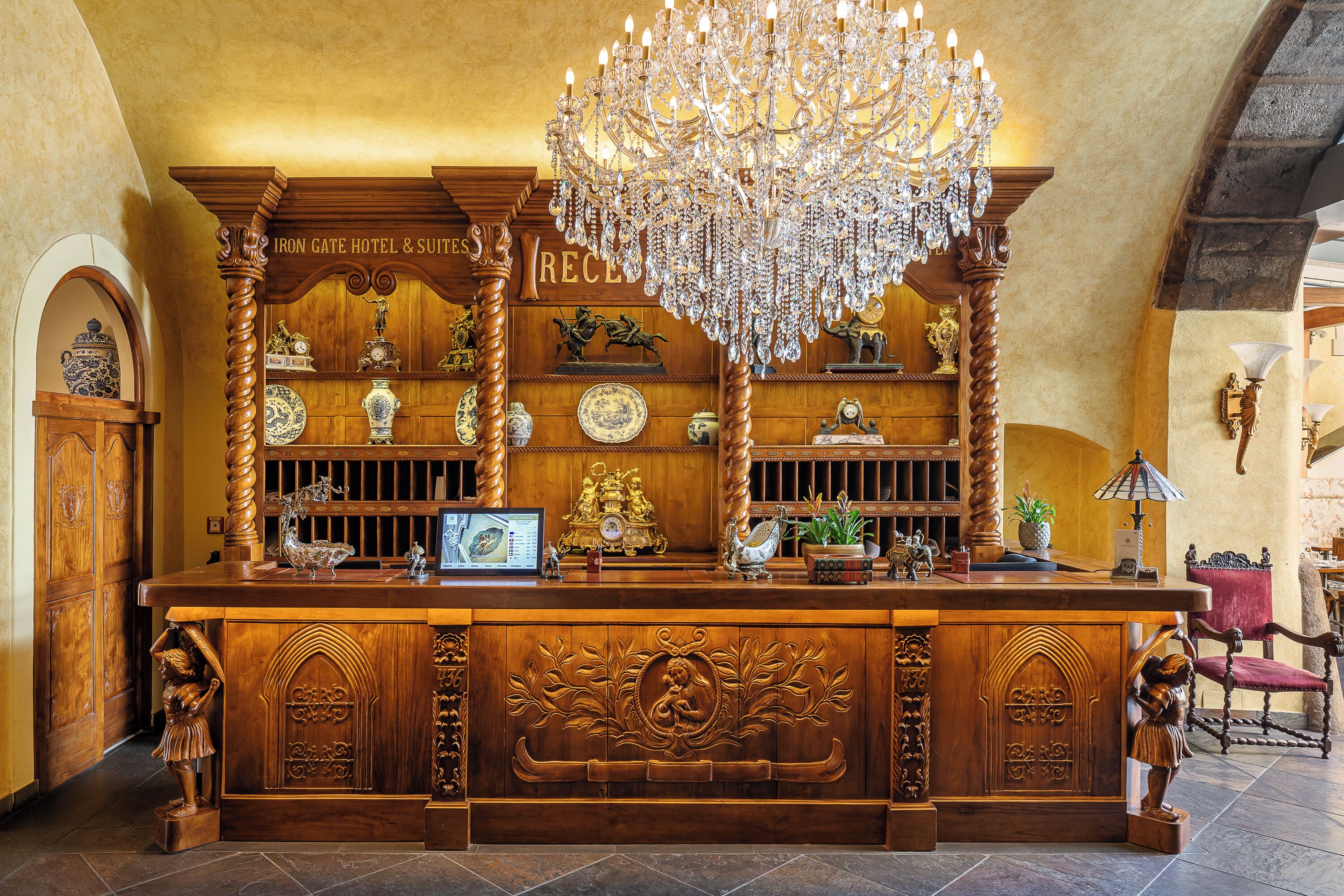 A reception desk with a wooden design, a chandelier, and various decorative items.