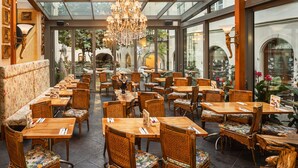 Un restaurante con mesas y sillas de madera, un candelabro y un techo de cristal.